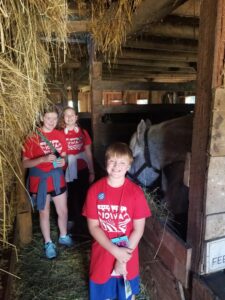 Children learning about horses inside an old barn.